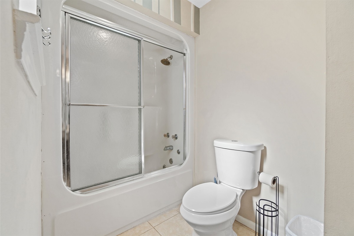 Clean and functional bathroom with a shower/tub combo and sliding glass doors—perfect for refreshing after a day of adventure."