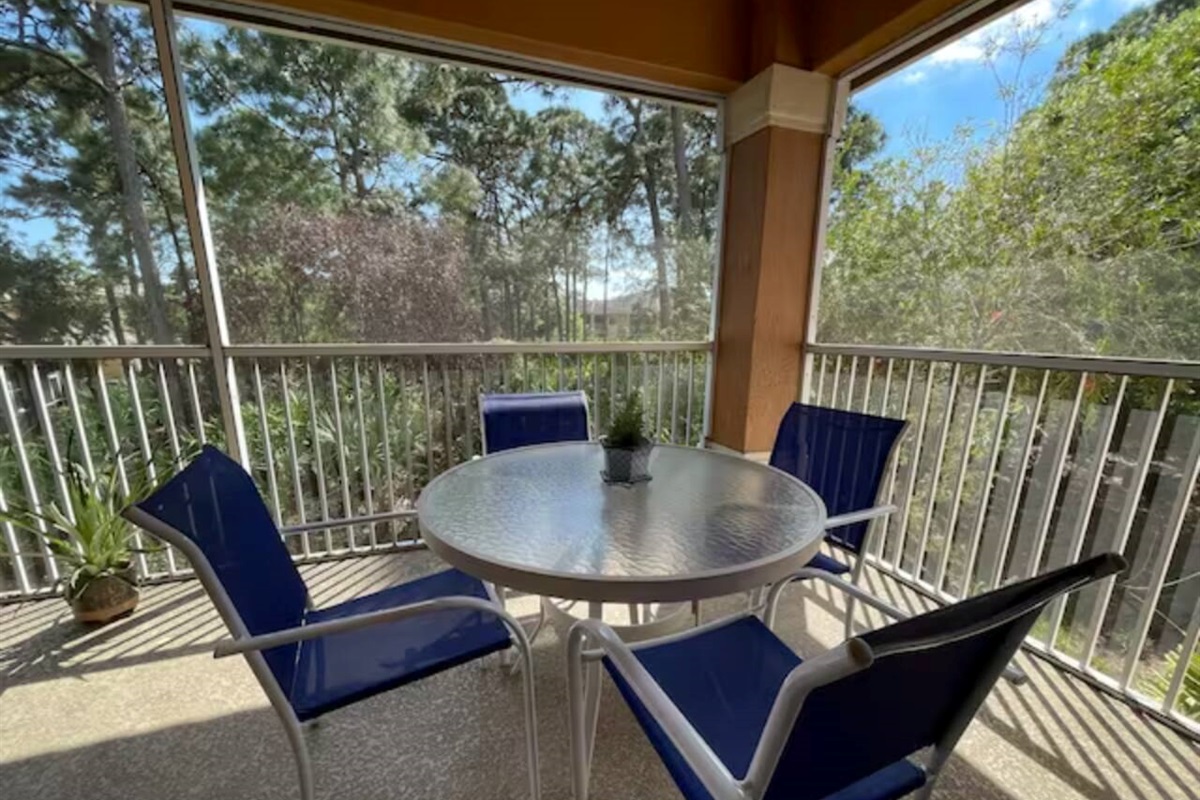 Private screened balcony with outdoor seating and peaceful views of the surrounding greenery.