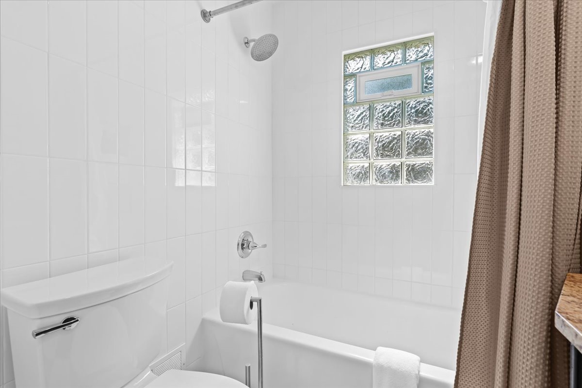 Clean, full-size shower with updated tile and glass block window