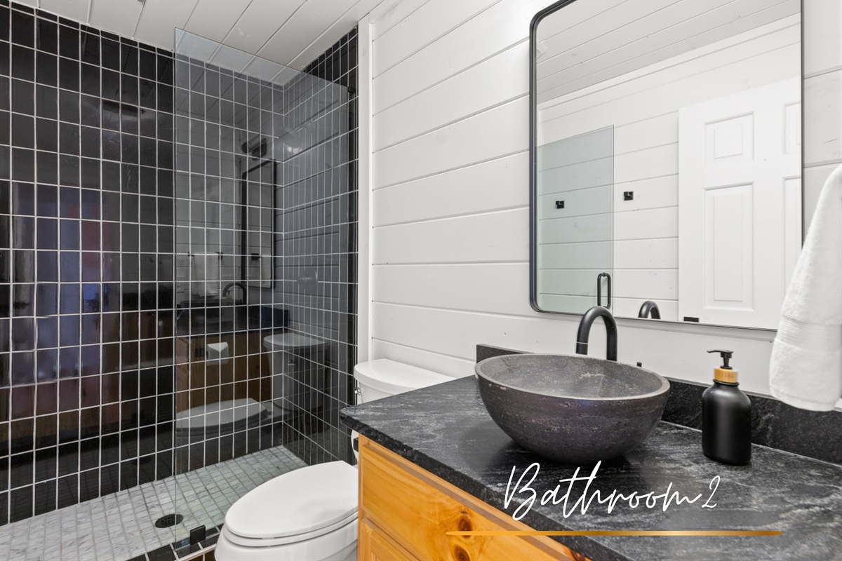 Stone sink and modern touches make this bathroom both functional and stylish.