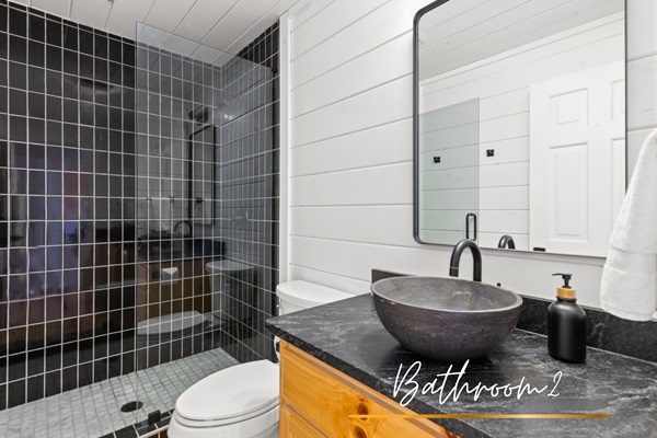 Stone sink and modern touches make this bathroom both functional and stylish.