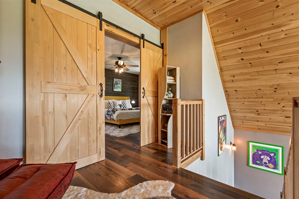 The second floor features a cozy reading loft, the master bedroom with king-size bed and barn door, a work space, and an ensuite bathroom.