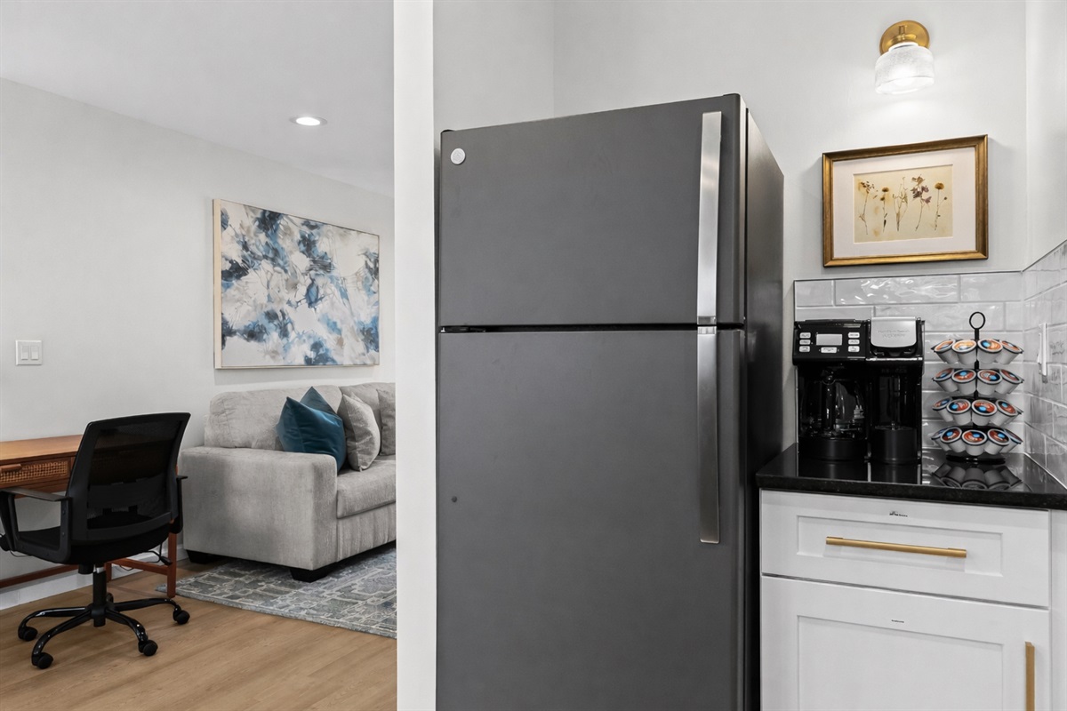 Modern kitchen with full-size fridge, sleek cabinetry, and a convenient coffee station—perfect for easy meals, morning brews, and longer stays.