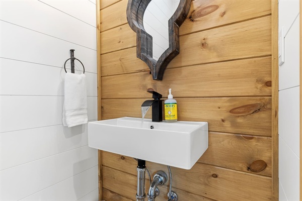 The half bath on the main level near the entry way has all the mountain house vibes with the natural wood accent wall, ceiling and door.