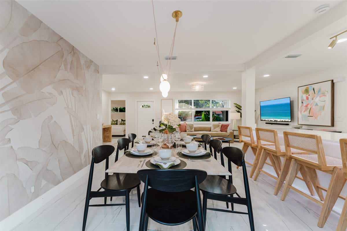 Designer dining room featuring a Gwyneth Paltrow GOOP statement light, custom wallpaper, and seating for 12. Backlit counter seating and seamless access to the patio and backyard make this space ideal for family meals and entertaining.