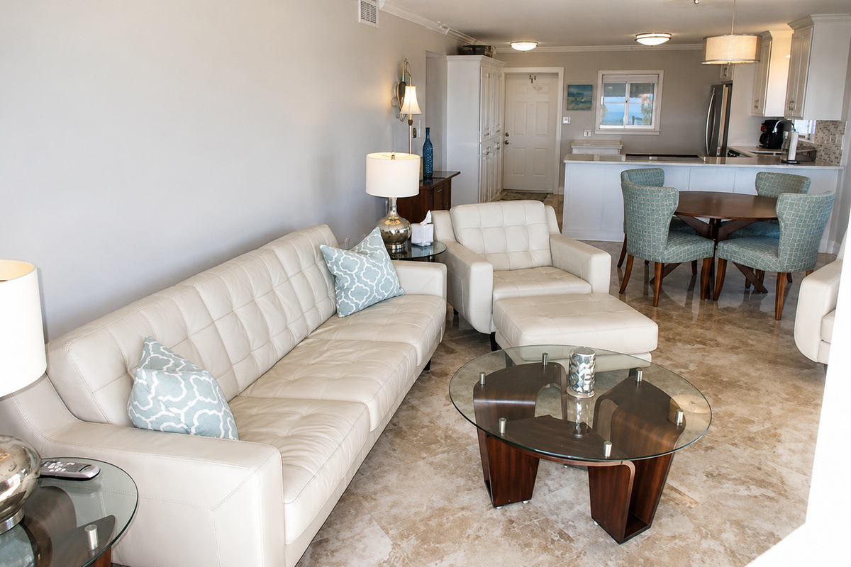 Modern living room with cream leather sofa, blue accents, and sleek open kitchen.