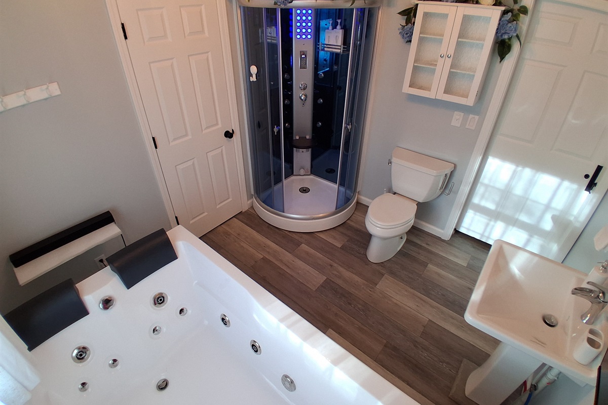 Step into your private spa unit, complete with a steam sauna and rainfall shower. Soft blue lighting sets a tranquil mood, and a built-in bench invites you to unwind. Just outside, a robe hook keeps towels or robes within reach.