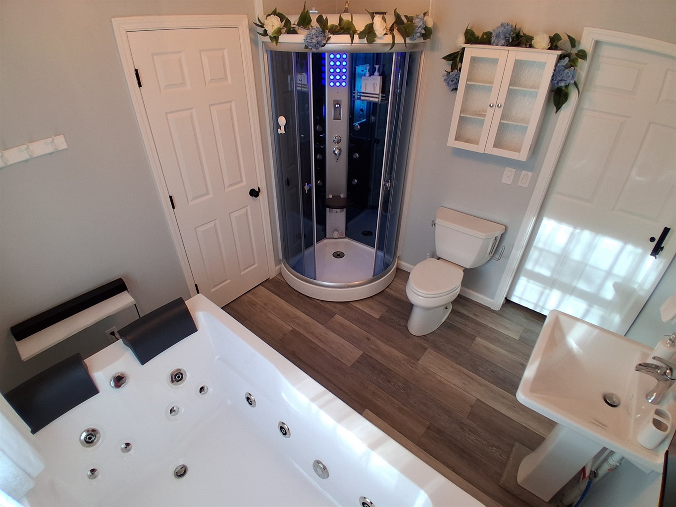Step into your private spa unit, complete with a steam sauna and rainfall shower. Soft blue lighting sets a tranquil mood, and a built-in bench invites you to unwind. Just outside, a robe hook keeps towels or robes within reach.