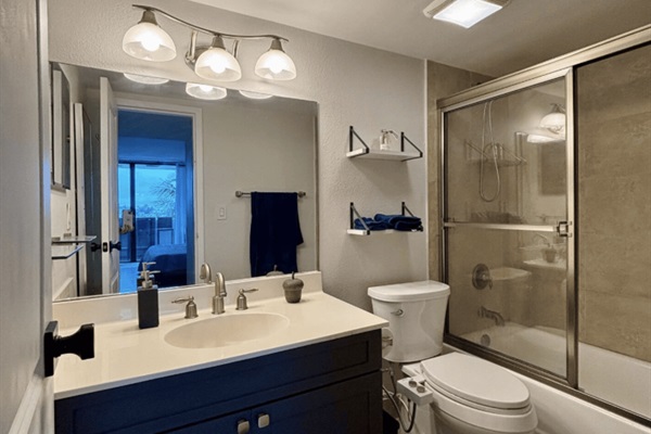 The bathroom is just off the bedroom, with a tub, shower and bathroom essentials.