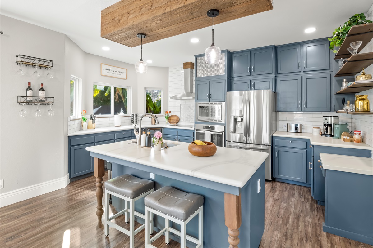 Fully stocked kitchen with stainless steel appliances, spacious island seating, coffee maker, toaster, and all the essentials needed to prepare family meals with ease.