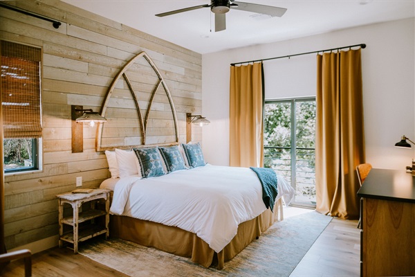 Bedroom #1 &mdash; a pillow-top king beneath a custom arched headboard, dressed in Comphy linens and warm upstairs light.