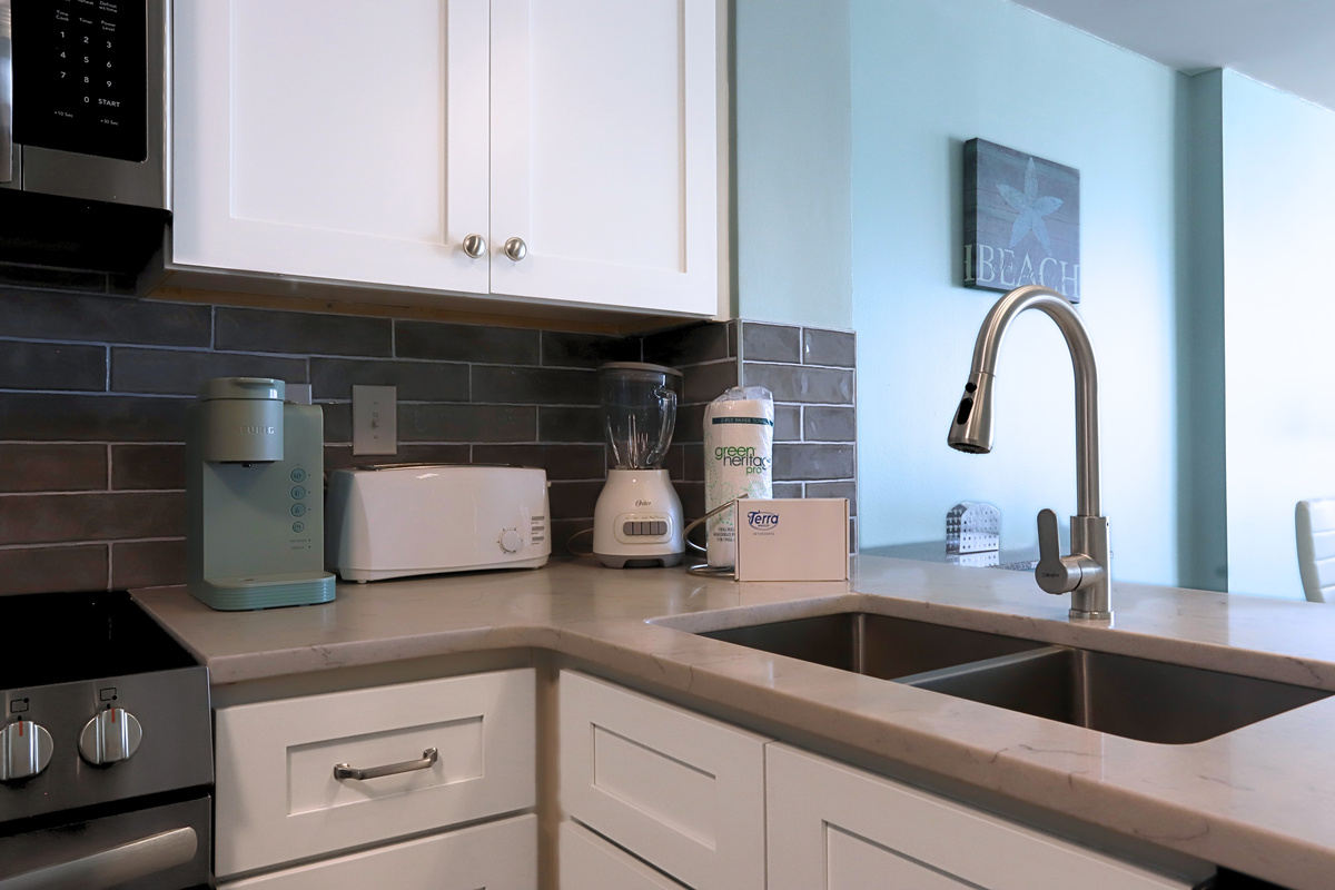 A modern kitchen featuring a sleek sink, coffee maker, blender, and an assortment of knives in various sizes—designed for convenience and efficiency in meal preparation.