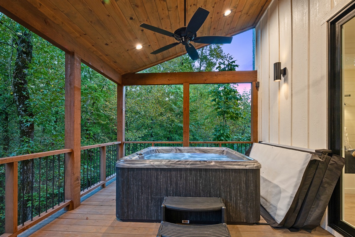 The hot tub sits under a covered porch, creating a relaxing place to unwind while still being sheltered from the elements.