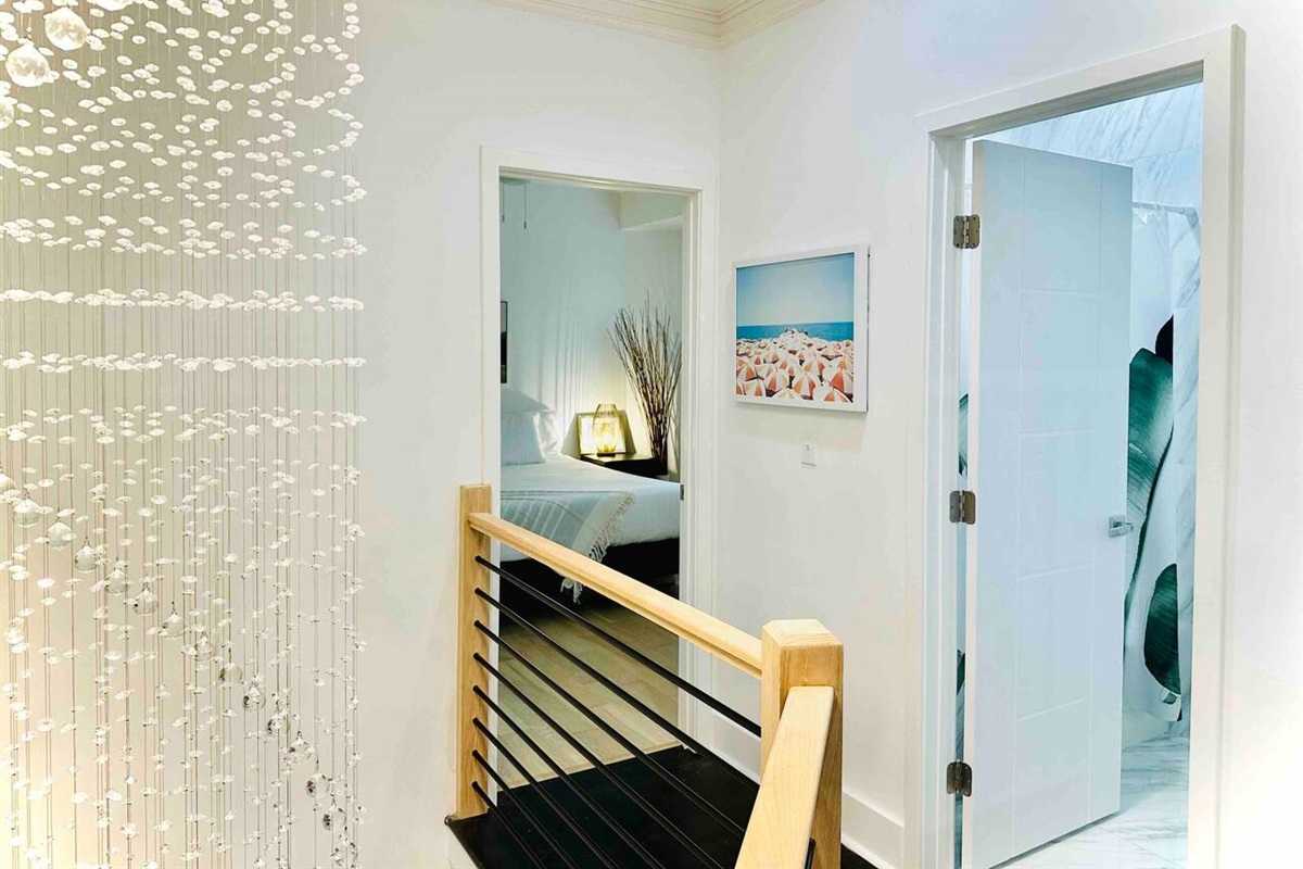 The rainfall chandelier starts on the top floor and falls through the stairwell down into the main floor. From here, you can peek into one of the King bedrooms and a full bathroom.
