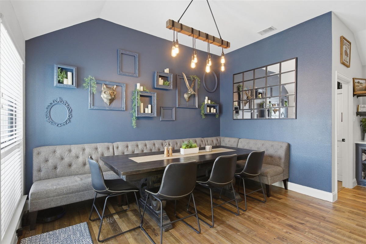 Open Dining Room featuring a Dining Table for 8, dramatic blue walls, a mirror gallery wall, and warm pendant lighting for memorable group dinners.
