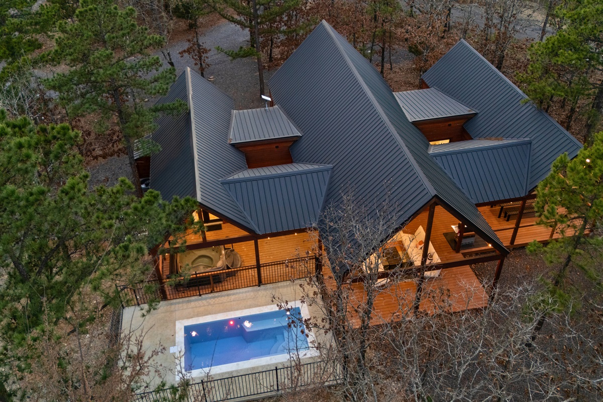 From above, the cabin’s unique rooflines and glowing lights create a welcoming retreat tucked right into the surrounding forest.