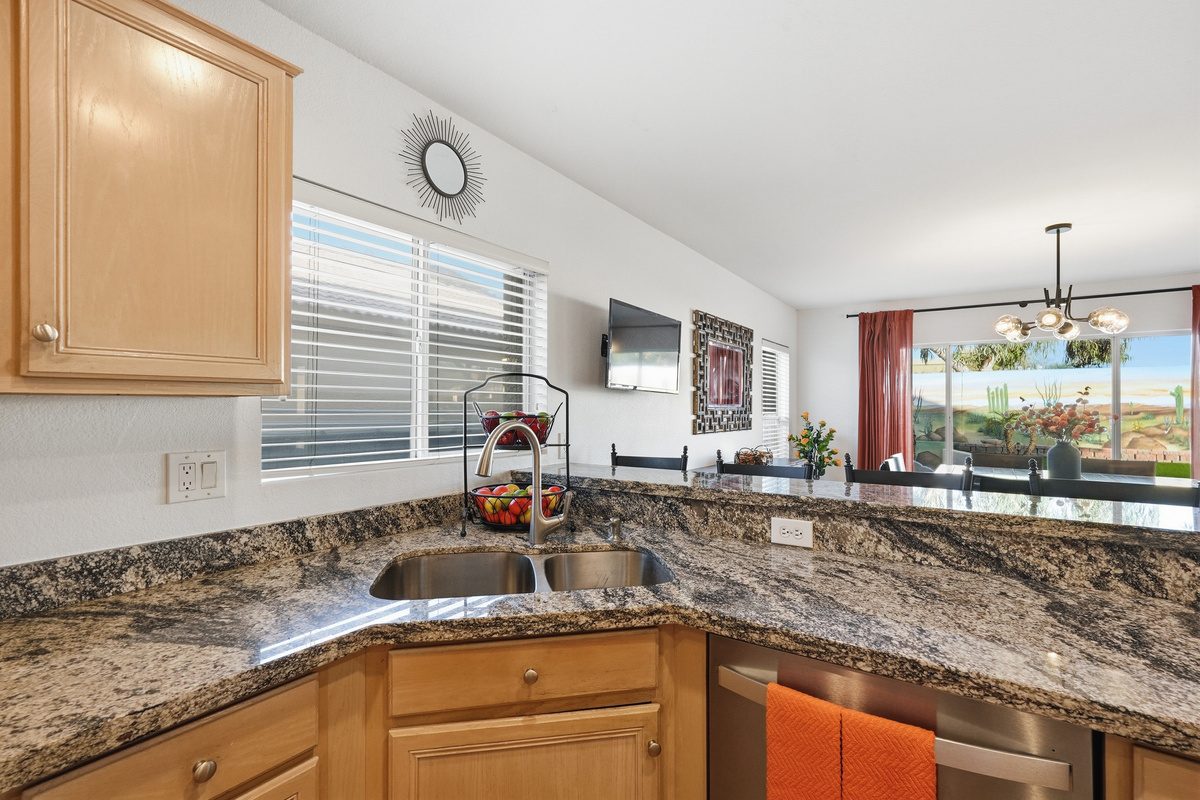Kitchen sink area with granite counters, dishwasher, and open views into the dining and living spaces.