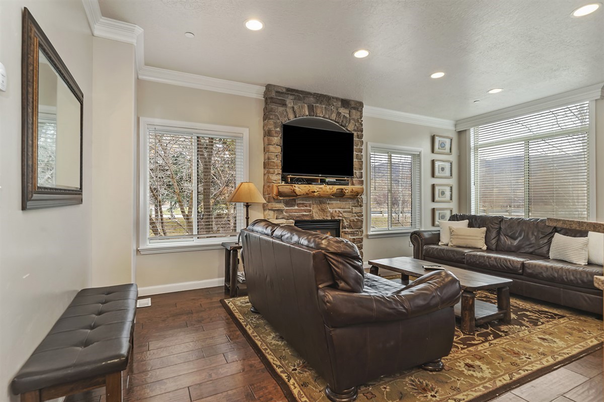 A beautifully appointed living room featuring a striking stone fireplace, plush seating, and abundant natural light—perfect for relaxing in elevated mountain comfort.