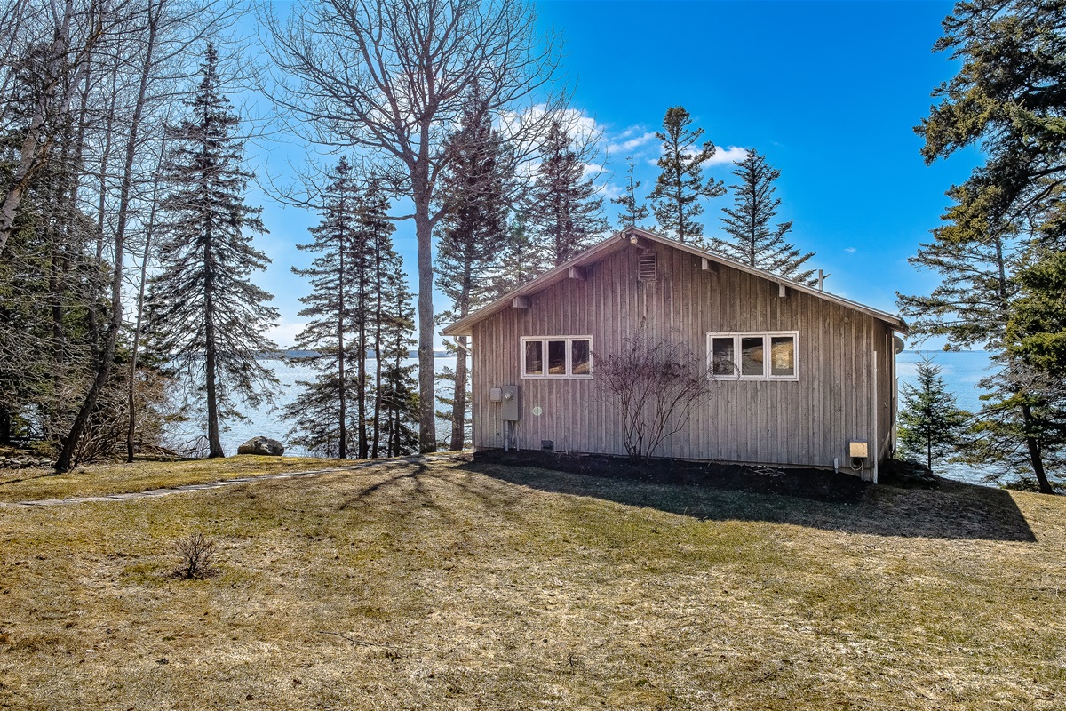 "A Seamless Arrival."
Navigate the full roundabout driveway with ease. This perspective shows the generous scale of the lot, nestled between the native pines with the blue of the harbor already visible on both sides of the home.