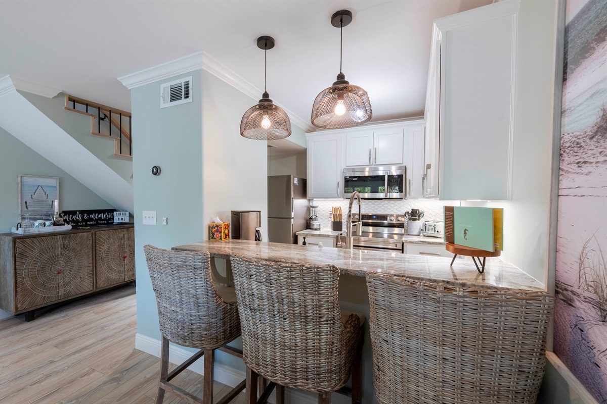Modern kitchen with wicker bar stools, pendant lights, and stainless appliances—perfect for family dining.
