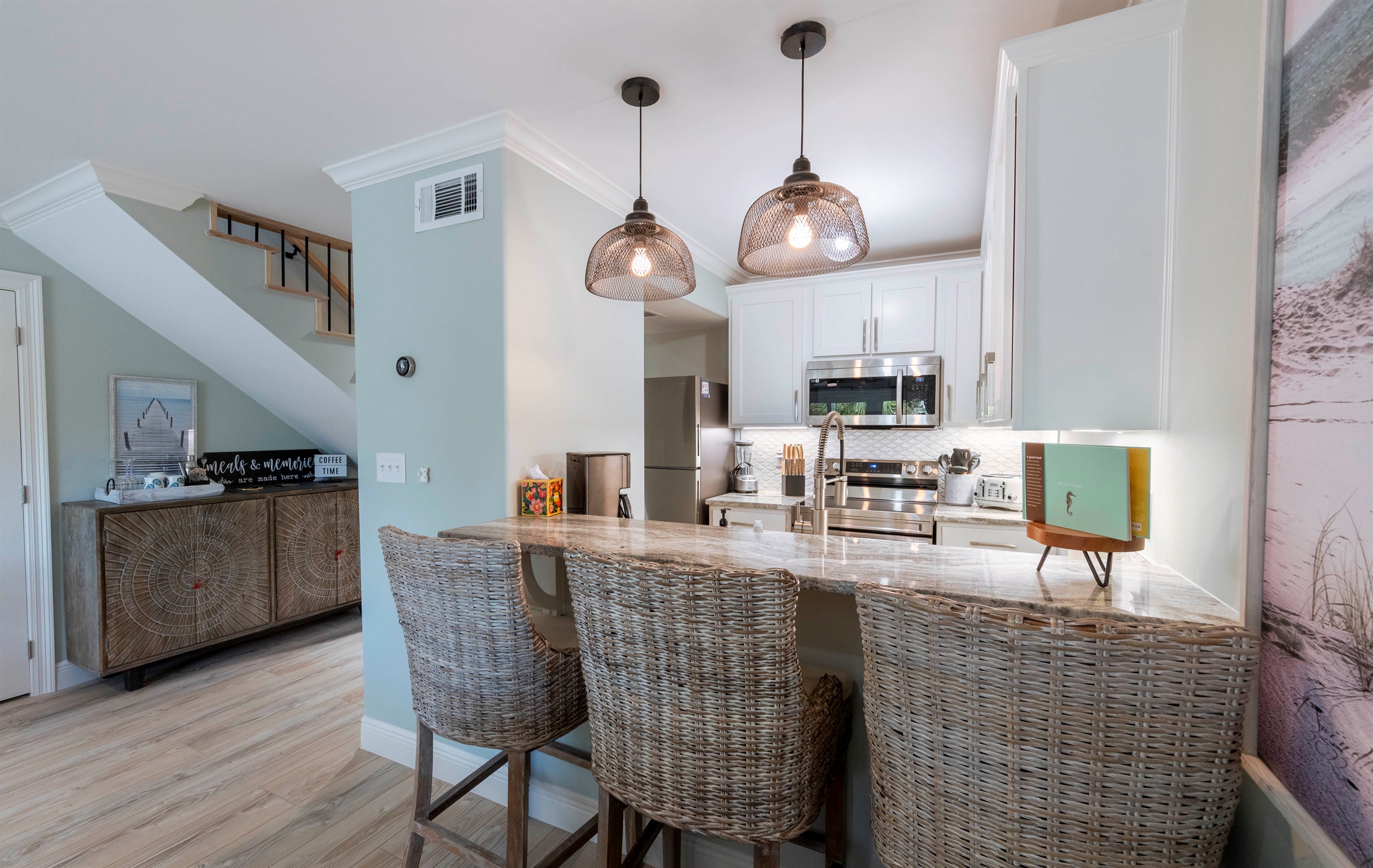 Modern kitchen with wicker bar stools, pendant lights, and stainless appliances—perfect for family dining.
