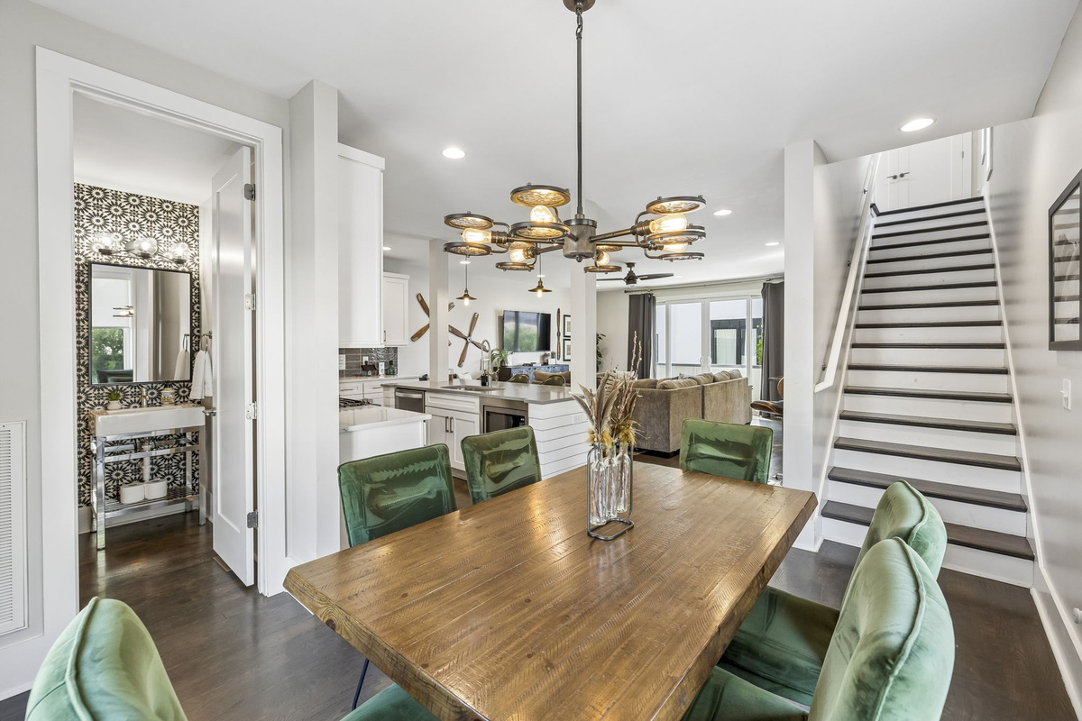 Light filled corner dining room with large windows and sleek contemporary layout - Olive green velvet chairs surround a warm wood table under a sculptural light fixture - Perfect for meals, board games, or casual coffee with natural sunlight all day