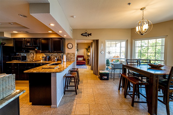Open kitchen and dining area with granite countertops, bar seating, and plenty of space for gathering.