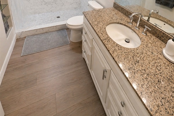 Bright and functional full bathroom featuring a spacious walk-in shower, granite vanity, and ample counter space. Clean finishes and good lighting make it perfect for everyday comfort and convenience.