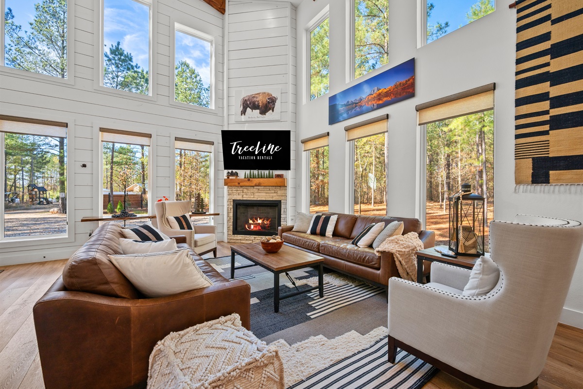 Tall windows frame views of the woods and flood the living area with beautiful natural light throughout the day.