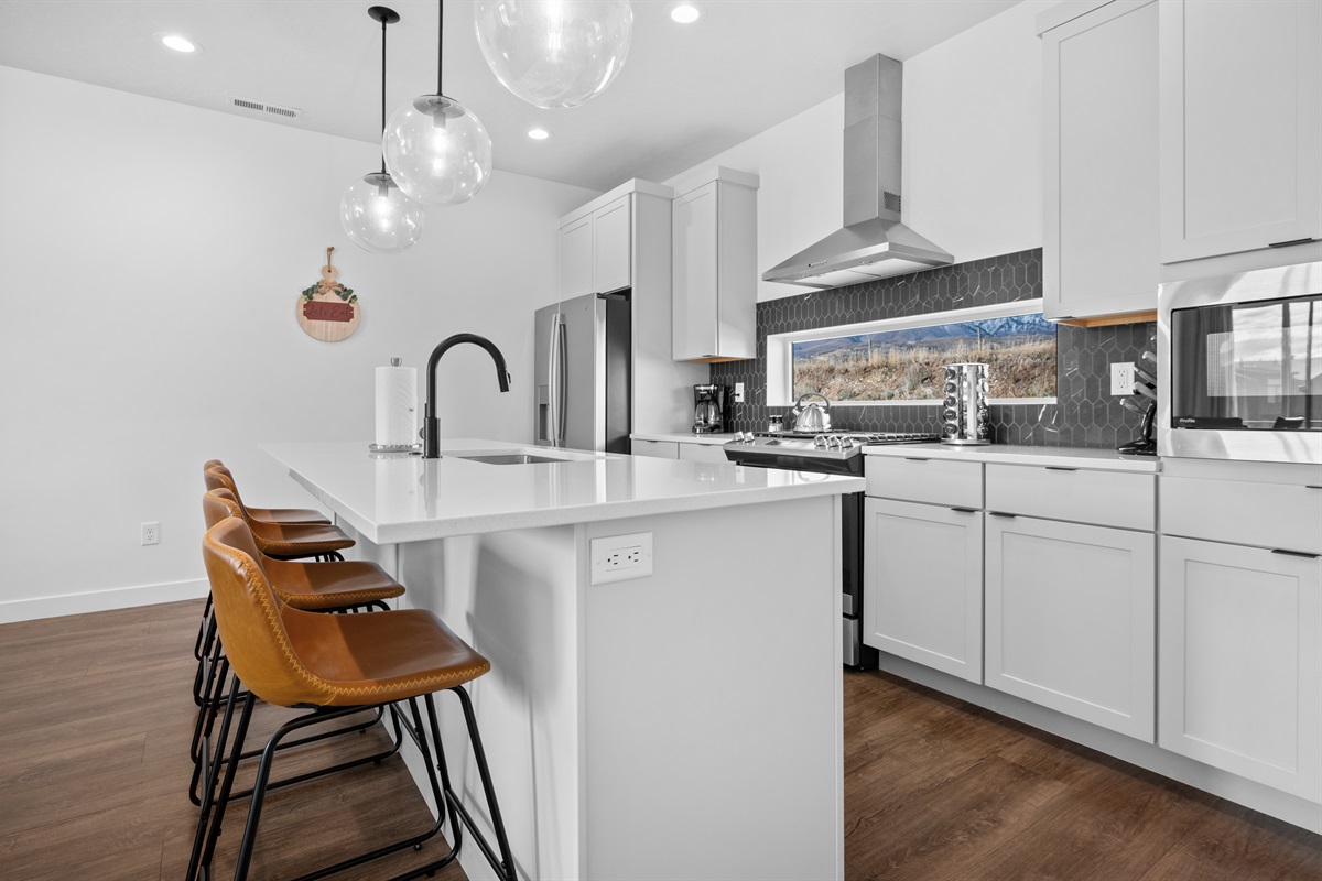 Fully equipped modern kitchen with quartz countertops and bar seating.