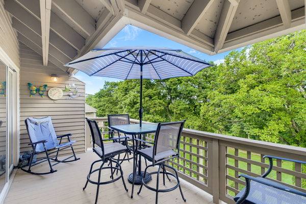 Relax on the partially covered private deck with outdoor dining, seating, and peaceful treetop views.