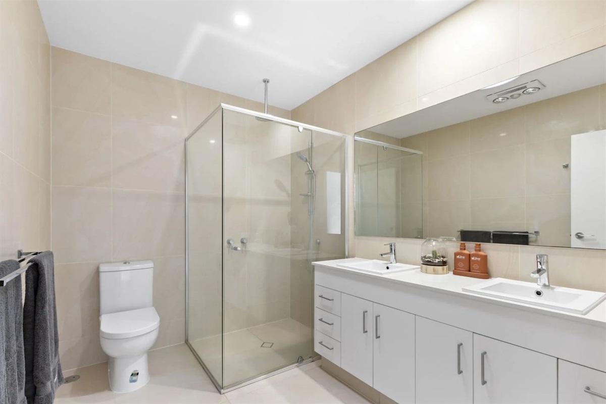 Stylish bathroom with a large glass-enclosed shower, spacious vanity, and sleek fixtures.