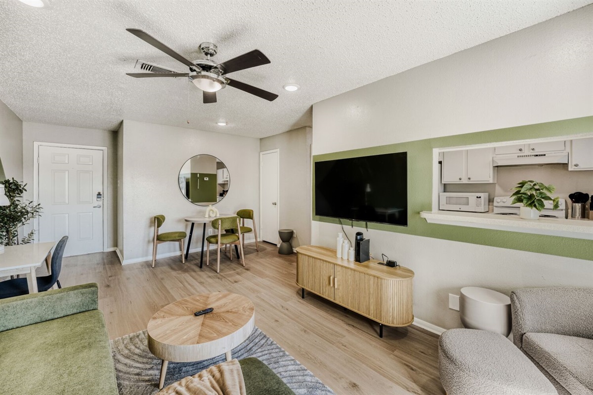 Modern living room with green accents, cozy seating, and an open layout.