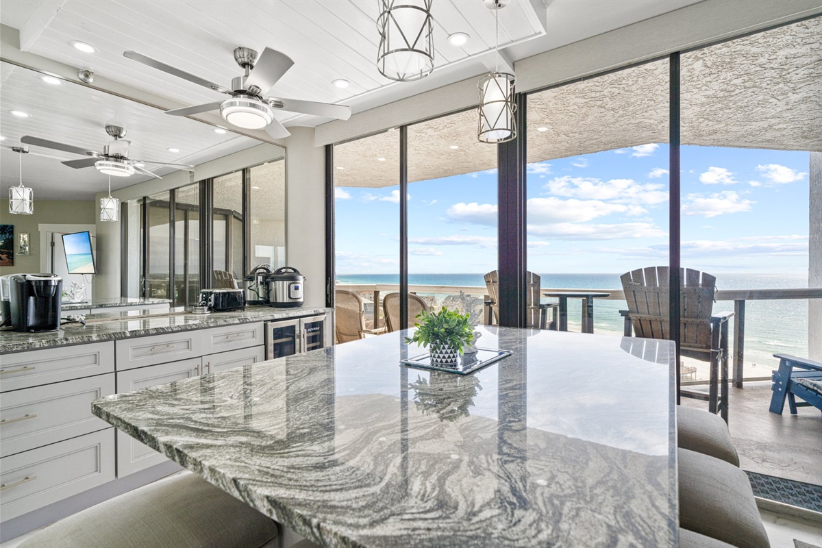The Gulf is not just a view from this kitchen. With the balcony doors open and the water filling the glass from corner to corner, it feels like a permanent part of the room itself.