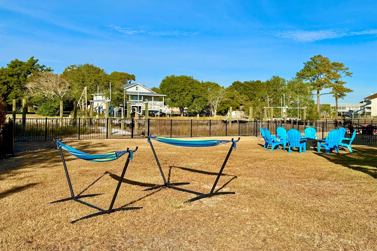 Private backyard dock with boat lift and fillet table, fenced-in backyard, fire pit with Adirondack chairs, hammocks, propane grill, picnic table, outdoor shower, expansive waterfront back deck, neighborhood boat ramp and dock