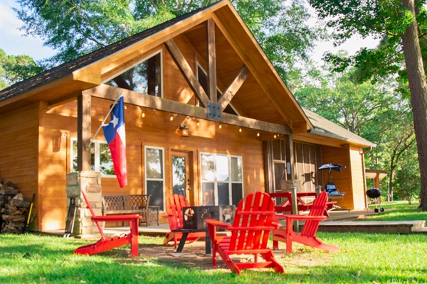 Lakefront cabin getaway with private dock, firepit & red Adirondack chairs — the Heart of Huxley Bay.