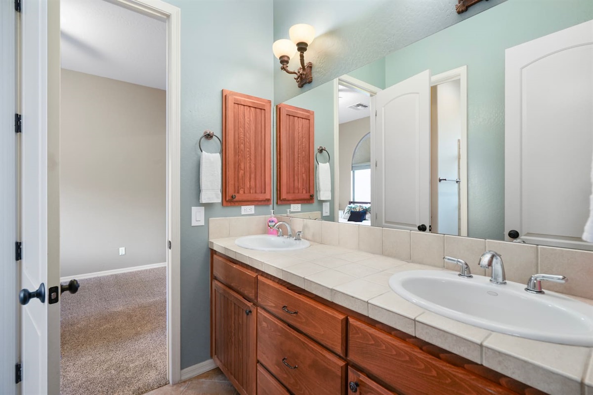 Shared bathroom featuring a spacious double vanity with ample counter space and warm wood cabinetry for added comfort and convenience.