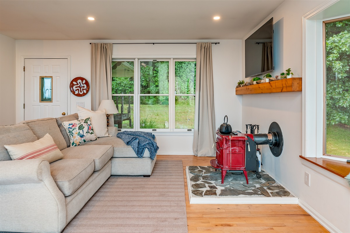 Bright and airy living space with large windows, wood floors, and forest views—relax in style with comfort all around