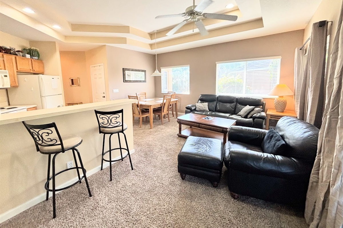 Updated living area with comfortable leather seating, open-concept layout, breakfast bar, dining space, and plenty of natural light.