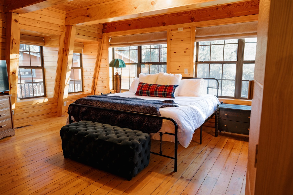 Wake to golden sunlight streaming through windows in the cozy bedroom at Poppywood Pines. This gothic western Show Low A-frame features plush bedding and rustic charm, perfect for restful nights after exploring White Mountains hiking trails and fishing.