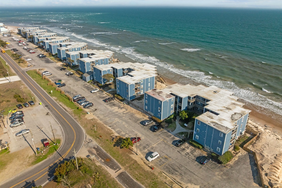Aerial view showing the oceanfront buildings and parking area off New River Inlet Road