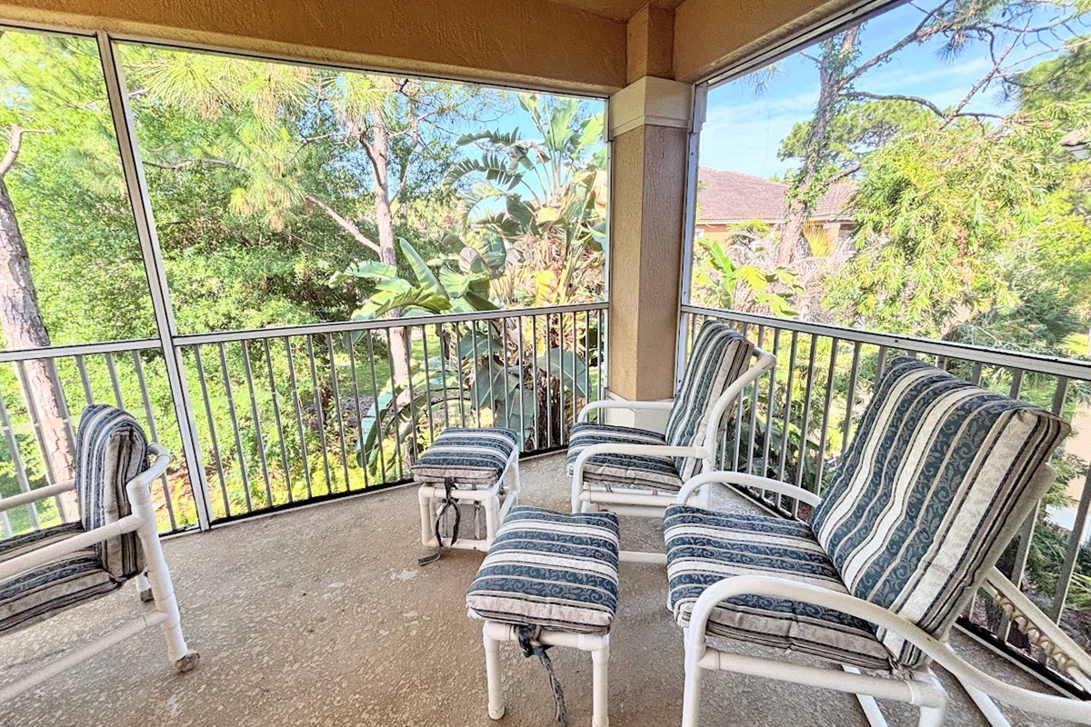 Private screened balcony with outdoor seating, offering a peaceful spot to relax and enjoy the surrounding greenery.
