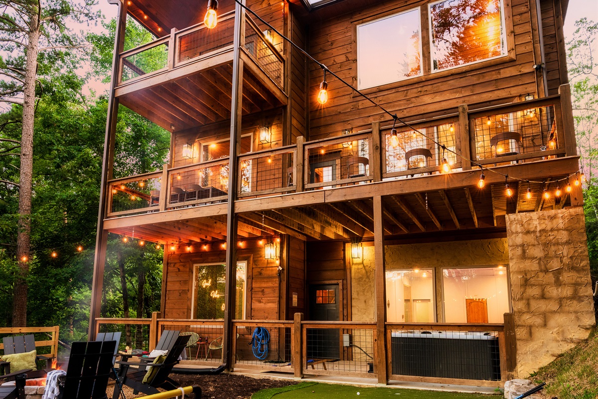 Luxury cabin with multiple decks, string lights, hot tub, and backyard with mini golf, fire pit, and outdoor games