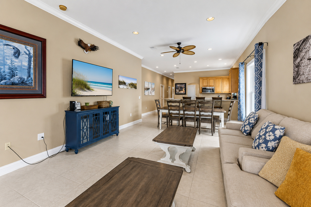 Great room flowing into the dining area and kitchen, anchored by a wall-mounted smart TV