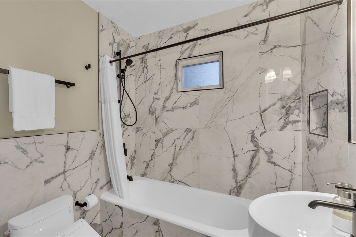 Unwind in this spa-inspired bathroom, complete with a deep soaking tub, rain shower, and elegant marble finishes