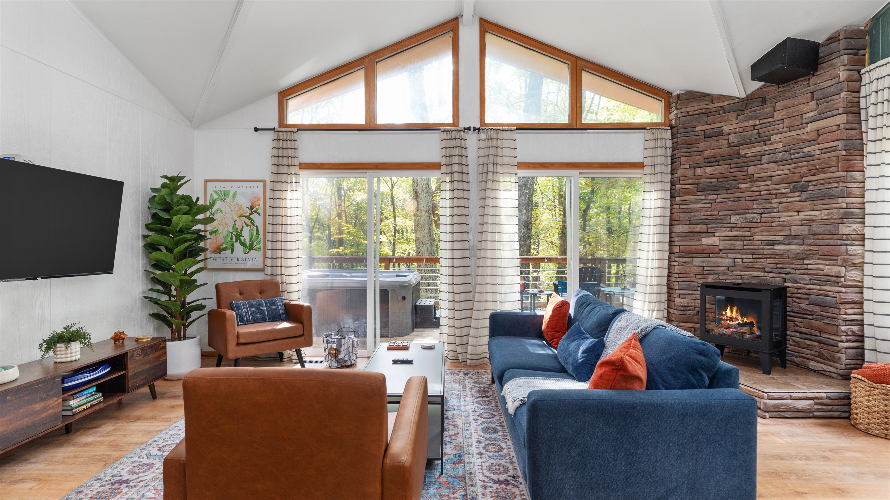 Spacious living room with cozy couch, Roku TV, and electric fireplace—high ceilings and easy deck access make it the perfect place to unwind.