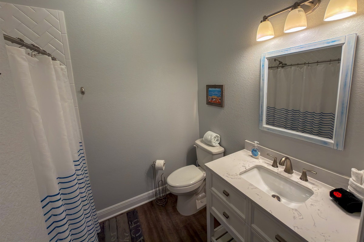 Ensuite Bathroom 2 features a walk-in shower, updated vanity, and subtle seaside décor that complements the home’s beachy atmosphere.