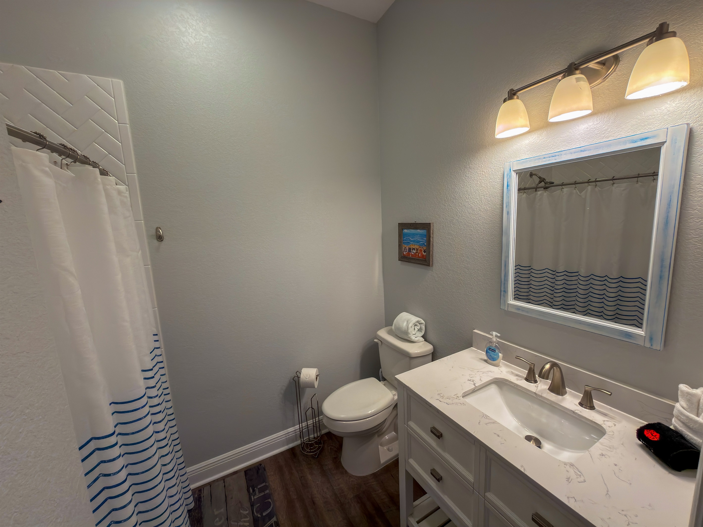 Ensuite Bathroom 2 features a walk-in shower, updated vanity, and subtle seaside décor that complements the home’s beachy atmosphere.