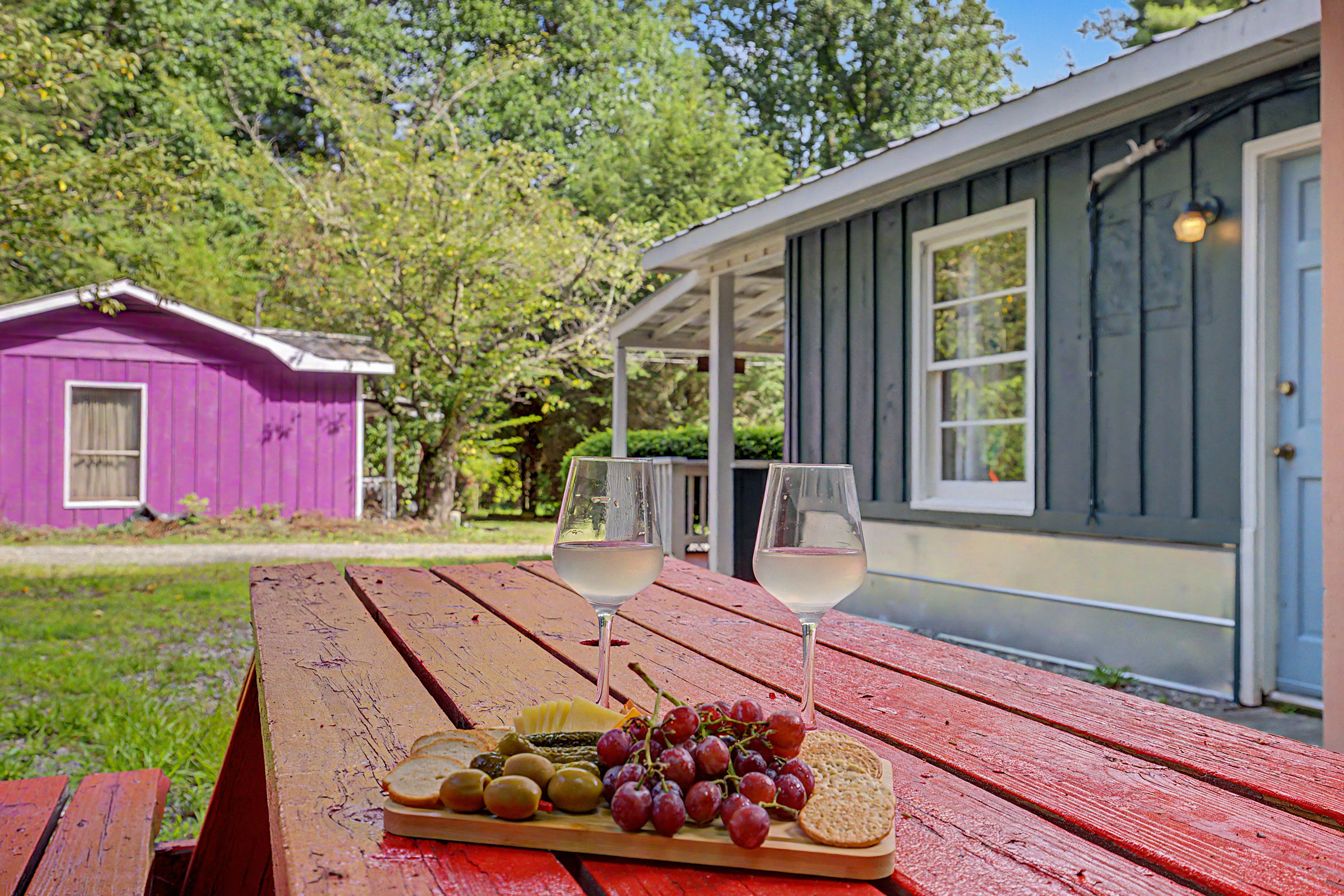 Outdoor Dining Space: Savor local wines and bites on a vibrant picnic table under leafy trees!