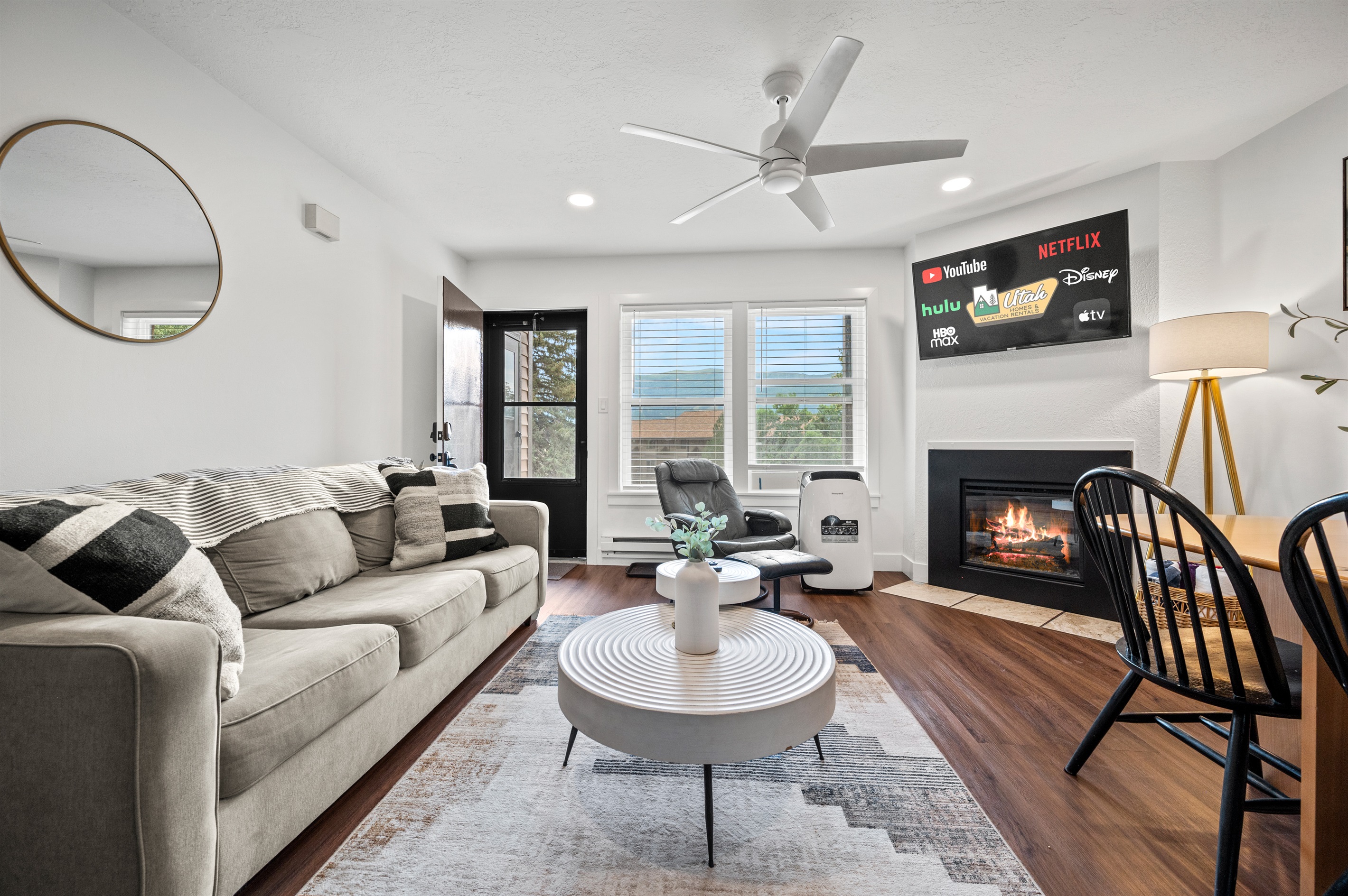 Experience the cozy living room, outfitted with plush seating, a fireplace, an expansive smart TV, and windows that frame the views of the great outdoors.